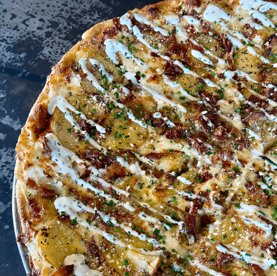 The Baked Potato Pie (Limited Time Only) Crafted with a tangy sour cream base, topped with grated pepper jack and mozzarella cheeses, thinly sliced potatoes, minced garlic, crumbled bacon, fresh rosemary and finished with parmesan and a drizzle of sour cream and chopped chives - A SGT. favorite!